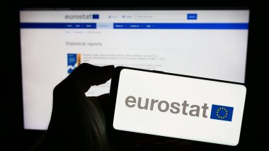 Stuttgart, Almanya - 11-02-2023: İnternet sayfası önünde AB kurumunun Avrupa İstatistik Bürosu Eurostat logosuna sahip cep telefonu sahibi kişi. Telefon ekranına odaklan.