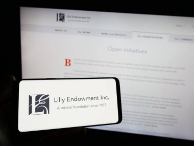 Stuttgart, Almanya - 11-02-2023: ABD vakfı Lilly Endowment Inc. 'in logosuna sahip akıllı telefon sahibi kişi web sitesinin önünde. Telefon ekranına odaklan.