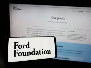 Stuttgart, Almanya - 11-02-2023: Amerikan yardım derneği Ford Foundation 'ın logosunu web sayfası önünde tutan kişi. Telefon ekranına odaklan.