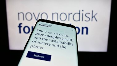 Stuttgart, Almanya - 11-02-2023: Danimarka organizasyonu Novo Nordisk Foundation 'ın web sitesiyle birlikte logo önünde cep telefonu. Telefon ekranının sol üst kısmına odaklan.