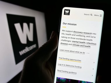 Stuttgart, Almanya - 11-02-2023: Logo önünde İngiliz Yardım Vakfı web sitesi ile cep telefonu tutan kişi. Telefon ekranının merkezine odaklan.