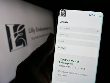 Stuttgart, Almanya - 11-02-2023: ABD vakfı Lilly Endowment Inc. 'in web sitesi ile logo önünde akıllı telefon tutan kişi. Telefon ekranının merkezine odaklan.