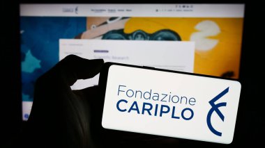 Stuttgart, Almanya - 11-03-2023: İtalyan yardım vakfı Fondazione Cariplo 'nun logosunu web sayfasının önünde tutan kişi. Telefon ekranına odaklan.