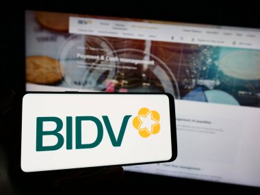 Stuttgart, Almanya - 11-03-2023: İnternet sayfası önünde Vietnam Yatırım ve Geliştirme için Ticaret Bankası logosu bulunan kişi. Telefon ekranına odaklan.