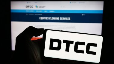 Stuttgart, Almanya - 11-03-2023: Web sayfası önünde ABD 'li Depository Trust and Clearing Corporation (DTCC) logosu olan kişi. Telefon ekranına odaklan.