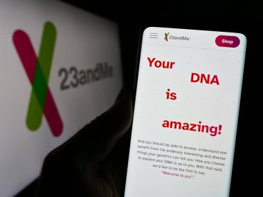 Stuttgart, Almanya - 11-03-2023: ABD 'li biyoteknoloji şirketi 23andMe Inc.' in internet sayfası ile cep telefonu tutan kişi iş logosu önünde. Telefon ekranının merkezine odaklan.