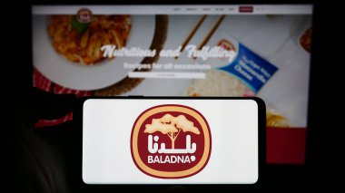 Stuttgart, Almanya - 11-03-2023: Katarlı süt ürünleri ve gıda şirketi Baladna 'nın logosuna sahip akıllı telefon sahibi kişi web sitesinin önünde. Telefon ekranına odaklan.