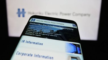 Stuttgart, Almanya - 11-03-2023: Japon enerji şirketi Hokuriku Electric Company 'nin web sitesi logo önünde cep telefonu. Telefon ekranının sol üst kısmına odaklan.