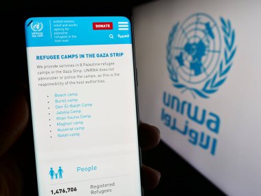 Stuttgart, Almanya - 11-03-2023: Birleşmiş Milletler Plalestine mülteci ajansı UNRWA 'nın web sitesiyle logo önünde akıllı telefon tutan kişi. Telefon ekranının merkezine odaklan.