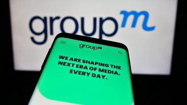 Stuttgart, Almanya - 11-03-2023: İş logosu önünde ABD 'li medya yatırım şirketi GroupM' nin web sitesiyle cep telefonu. Telefon ekranının sol üst kısmına odaklan.
