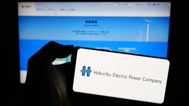 Stuttgart, Almanya - 11-03-2023: İnternet sayfası önünde Japon enerji şirketi Hokuriku Electric Company 'nin logosuna sahip kişi. Telefon ekranına odaklan.