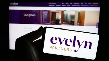 Stuttgart, Almanya - 11-06-2023: İngiliz finans hizmetleri şirketi Evelyn Partners 'ın logosunun bulunduğu akıllı telefon sahibi kişi web sitesi önünde. Telefon ekranına odaklan.