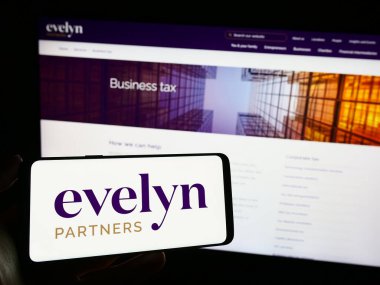 Stuttgart, Almanya - 11-06-2023: İngiliz finans hizmetleri şirketi Evelyn Partners 'ın logosunun bulunduğu cep telefonu sahibi kişi iş sayfasının önünde. Telefon ekranına odaklan.