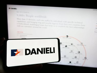 Stuttgart, Almanya - 11-06-2023: İtalyan Danieli C. Officine Meccaniche SpA şirketinin logosunun bulunduğu cep telefonu sahibi kişi iş sayfasının önünde. Telefon ekranına odaklan.