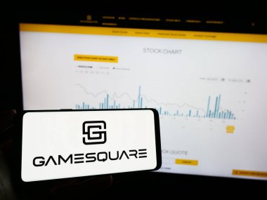 Stuttgart, Almanya - 11-06-2023: Kanadalı e-spor şirketi GameSquare Holding Inc. 'in logosu olan cep telefonu sahibi kişi iş sayfasının önünde. Telefon ekranına odaklan.