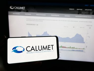 Stuttgart, Almanya - 11-06-2023: Amerikan şirketi Calumet Specialty Products Partners 'ın logosuna sahip cep telefonu sahibi kişi web sayfasının önünde. Telefon ekranına odaklan.