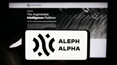 Stuttgart, Almanya - 11-07-2023: Alman yapay zeka şirketi Aleph Alpha GmbH 'nin logosuna sahip akıllı telefon sahibi kişi web sitesinin önünde. Telefon ekranına odaklan.