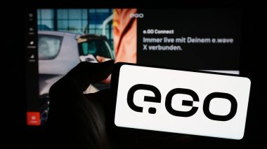 Stuttgart, Almanya - 11-07-2023: Alman elektrikli araç şirketi Next.e.GO Mobile SE 'nin logosuna sahip cep telefonu sahibi kişi web sayfasının önünde. Telefon ekranına odaklan.