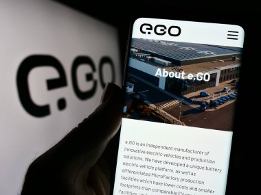 Stuttgart, Almanya - 11-07-2023: Alman elektrikli araç şirketi Next.e.GO Mobile SE 'nin web sitesi ile logo önünde akıllı telefon tutan kişi. Telefon ekranının merkezine odaklan.