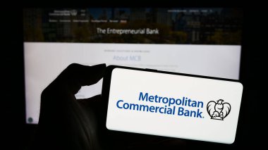 Stuttgart, Almanya - 11-07-2023: ABD 'li finans şirketi Metropolitan Commercial Bank' ın (MCB) logosuna sahip akıllı telefon sahibi kişi web sitesi önünde. Telefon ekranına odaklan.