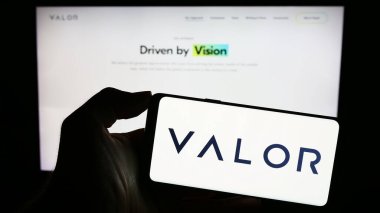 Stuttgart, Almanya - 11-07-2023: Amerikan yatırım şirketi Valor Capital Group LLC 'nin logosuna sahip cep telefonu sahibi kişi web sayfasının önünde. Telefon ekranına odaklan.
