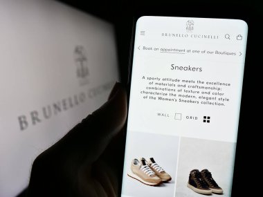 Stuttgart, Almanya - 11-07-2023: İtalyan moda şirketi Brunello Cucinelli S.P.A. 'nın internet sitesiyle cep telefonu tutan kişi logonun önünde. Telefon ekranının merkezine odaklan.