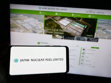 Stuttgart, Almanya - 11-08-2023: Japon enerji şirketi Japan Nuclear Fuel Ltd. (JNFL) 'nin logosuna sahip akıllı telefon sahibi kişi web sitesinin önünde. Telefon ekranına odaklan.