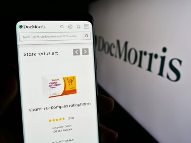 Stuttgart, Almanya - 11-08-2023: İsviçreli online eczane şirketi DocMorris AG 'nin internet sayfası ile logo önünde akıllı telefon tutan kişi. Telefon ekranının merkezine odaklan.