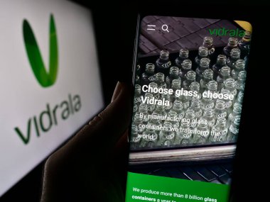 Stuttgart, Almanya - 11-08-2023: İspanyol cam imalat şirketi Vidrala S.A. 'nın internet sayfası ile logo önünde cep telefonu tutan kişi. Telefon ekranının merkezine odaklan.