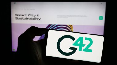 Stuttgart, Almanya - 11-08-2023: Emirati teknoloji şirketi Group 42 Holding Ltd. 'nin logosuyla cep telefonu tutan kişi. (G42) İnternet sayfasının önünde. Telefon ekranına odaklan.