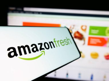 Stuttgart, Almanya - 11-09-2023: Amerikan market perakende şirketi Amazon Fresh 'in logosuna sahip akıllı telefon iş sitesinin önünde. Telefon ekranının soluna odaklan.