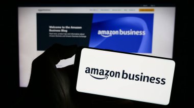 Stuttgart, Almanya - 11-09-2023: ABD 'li B2B e-ticaret platformu şirketi Amazon Business' ın logosunu taşıyan cep telefonu sahibi iş sayfası önünde. Telefon ekranına odaklan.