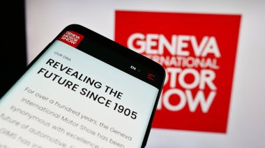 Stuttgart, Almanya - 11-10-2023: İş logosu önünde Cenevre Uluslararası Otomobil Fuarı 'nın web sitesi bulunan cep telefonu. Telefon ekranının sol üst kısmına odaklan.