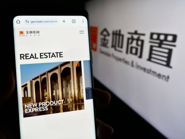 Stuttgart, Almanya - 11-10-2023: Gemdale Gayrimenkul ve Yatırım Şirketi 'nin web sayfası ile logonun önünde cep telefonu tutan kişi. Telefon ekranının merkezine odaklan.