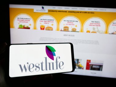 Stuttgart, Almanya - 11-10-2023: Hint fast food şirketi Westlife Foodworld Limited 'in logosuna sahip cep telefonu sahibi kişi web sayfasının önünde. Telefon ekranına odaklan.