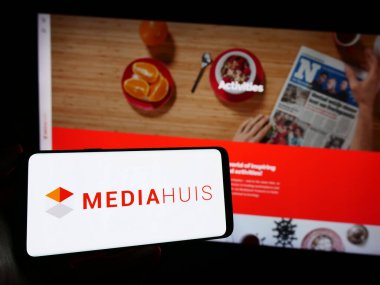 Stuttgart, Almanya - 11-10-2023: Belçikalı medya şirketi Mediahuis N.V. 'nin logosuna sahip akıllı telefon sahibi kişi web sitesinin önünde. Telefon ekranına odaklan.