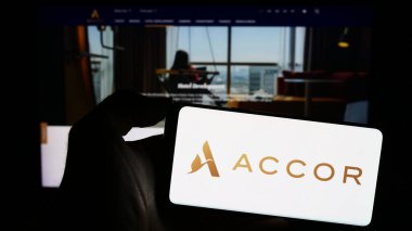Stuttgart, Almanya - 11-10-2023: Fransız konukseverlik şirketi Accor S.A. 'nın logosuyla cep telefonu tutan kişi iş sayfasının önünde. Telefon ekranına odaklan.