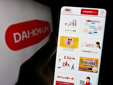 Stuttgart, Almanya - 11-11-2023: Japon şirketi Dai-ichi Hayat Sigortası Şirketi 'nin logolu internet sitesi ile cep telefonu tutan kişi. Telefon ekranının merkezine odaklan.