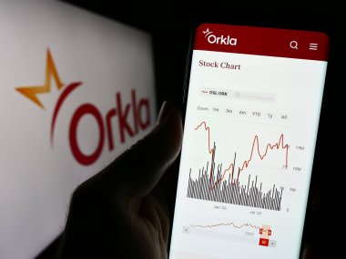 Stuttgart, Almanya - 11-11-2023: Norveçli firma Orkla ASA 'nın internet sayfası ile iş logosu önünde cep telefonu tutan kişi. Telefon ekranının merkezine odaklan.