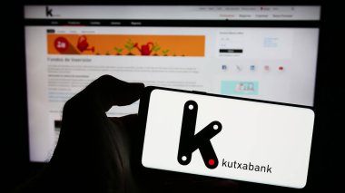 Stuttgart, Almanya - 11-11-2023: İspanyol finans hizmetleri şirketi Kutxabank S.A. 'nın logosuyla cep telefonu tutan kişi iş sayfasının önünde. Telefon ekranına odaklan.