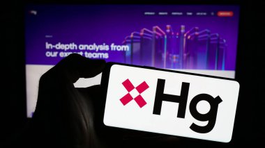 Stuttgart, Almanya - 11-11-2023: İçinde teknoloji yatırım şirketi Hg Capital 'in logosu bulunan cep telefonu sahibi kişi iş sayfasının önünde. Telefon ekranına odaklan.