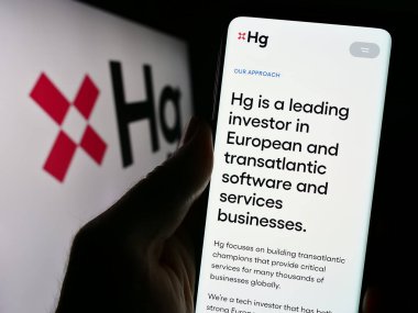 Stuttgart, Almanya - 11-11-2023: İş logosu önünde teknoloji yatırım şirketi Hg Capital 'in web sayfası ile cep telefonu tutan kişi. Telefon ekranının merkezine odaklan.