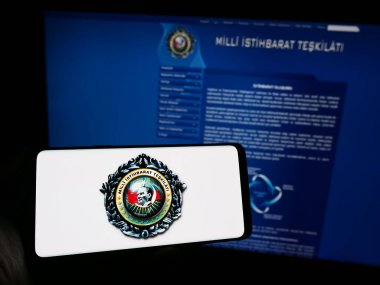 Stuttgart, Almanya - 11-12-2023: İnternet sayfası önünde Türk istihbarat teşkilatı Milli Istithe Teskilati 'nin (MIT) logosuyla cep telefonu tutan kişi. Telefon ekranına odaklan.