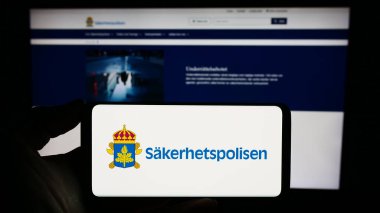 Stuttgart, Almanya - 11-12-2023: İnternet sitesi önünde üzerinde İsveç güvenlik servisi Sakerhetspolisen (SPO) logosu bulunan kişi. Telefon ekranına odaklan.