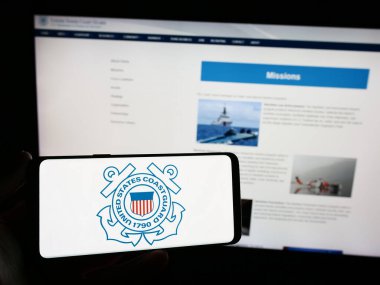 Stuttgart, Almanya - 11-12-2023: İnternet sitesi önünde ABD Sahil Güvenlik (USCG) mührü taşıyan kişi. Telefon ekranına odaklan.