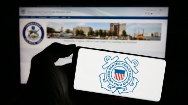 Stuttgart, Almanya - 11-12-2023: İnternet sayfası önünde ABD Sahil Güvenlik (USCG) mührü taşıyan kişi. Telefon ekranına odaklan.
