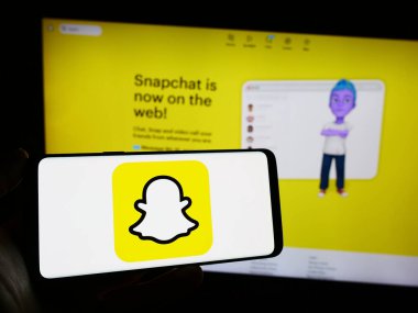 Stuttgart, Almanya - 11-14-2023: ABD multimedya anında mesajlaşma uygulaması Snapchat 'in logosunun bulunduğu cep telefonu sahibi şirket web sayfası önünde. Telefon ekranına odaklan.
