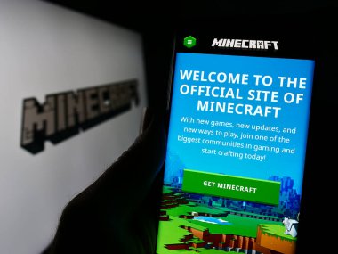 Stuttgart, Almanya - 11-14-2023: Logo önündeki kum havuzu video oyunu Minecraft web sayfası ile cep telefonu tutan kişi. Telefon ekranının merkezine odaklan.