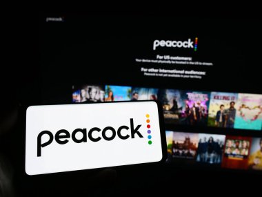 Stuttgart, Almanya - 11-14-2023: İnternet sitesi önünde ABD 'li video yayın hizmeti şirketi Peacock TV LLC' nin logosuna sahip kişi. Telefon ekranına odaklan.