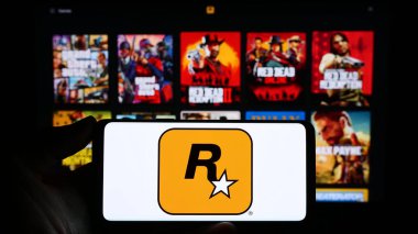 Stuttgart, Almanya - 11-14-2023: ABD 'li video oyunu yayıncılık şirketi Rockstar Games Inc.' in logosuna sahip akıllı telefon sahibi kişi web sitesi önünde. Telefon ekranına odaklan.
